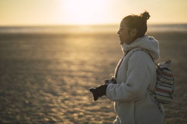Sonbahar akşamı denizde yürüyüş yapan montlu bir kız.