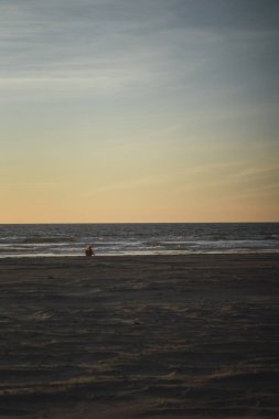 Gün batımında sahilde bir insanın silueti.