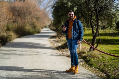 Yakışıklı bir adam baharda köpeğiyle parkta yürüyor.