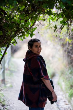 Omuzlarında sırt çantasıyla ormanda genç bir kadın.