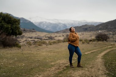 Sırt çantalı genç bir kadın yolda duruyor.