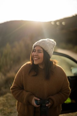 Genç, güzel esmer kadın sonbahar ormanında kamera önünde poz veriyor.