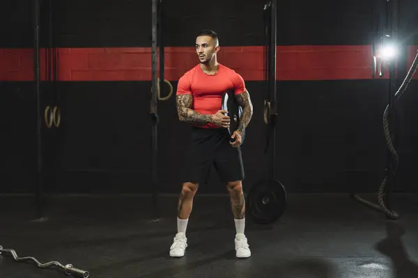 Genç adam kettlebell ile egzersiz yapıyor.