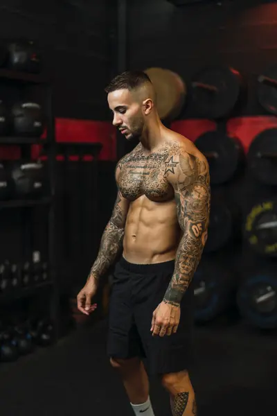 Yakışıklı kaslı adam spor salonunda ağır ağırlık egzersizi yapıyor.