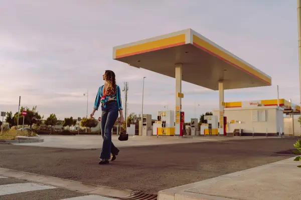 Benzin istasyonunda duran genç bir kadın..