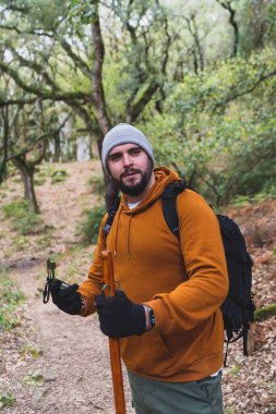 Genç adam ormanda sırt çantasıyla yürüyüş yapıyor.