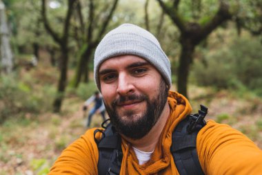 Ormanda sakallı genç bir adam, sırt çantası ve kamerası olan bir turist..