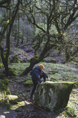Genç adam kayaya tırmanıyor.