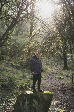 Sırt çantası ve yerde şapkası olan ormanda bir adam.
