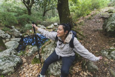 Sırt çantalı bir kadın ormanda selfie çekiyor.