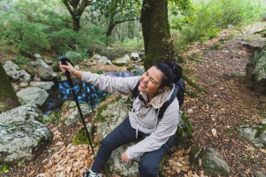 Sırt çantalı genç bayan yürüyüşçü fotoğraf çekiyor.