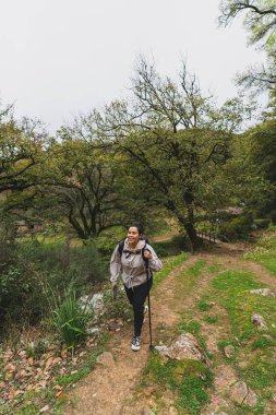 Sırt çantasıyla ormanda yürüyüş yapan genç bir kadın.