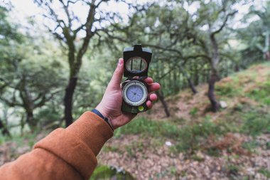 Ormanda pusulası ve akıllı telefonu olan bir adam.