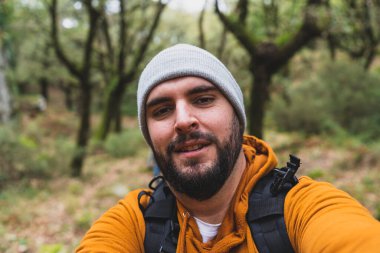 Sırt çantalı sakallı bir adam yürüyüş yapıyor.