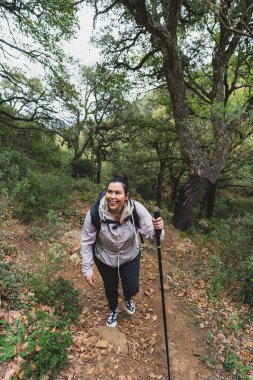 Sırt çantalı genç kız ormanda yürüyüş yapıyor.