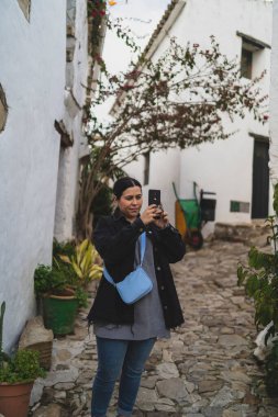 Taormina 'da akıllı telefon kullanan genç bir kadın, Sicilya, İtalya.