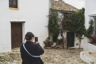 Köyde cep telefonunun fotoğraflarını çeken bir kadın.