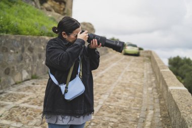 Genç fotoğrafçı kamerayla fotoğraf çekiyor.