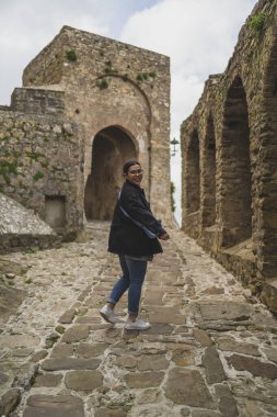 Eski Kudüs şehrinde sırt çantalı siyah elbiseli genç bir kadın.