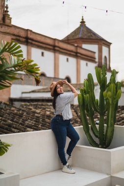 Bahçede kaktüsle terasta poz veren genç bir kadın.