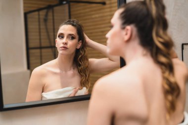 Banyodaki kadın aynaya bakıyor.