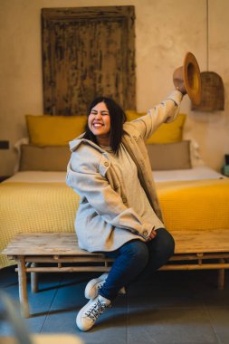 Genç Asyalı kadın yatakta oturuyor ve gülümsüyor..