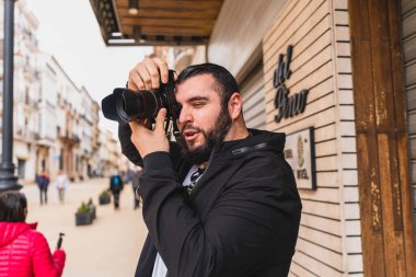 Yakışıklı, genç, sakallı turist fotoğrafçı Seville, İspanya 'da eski model bir kamerayla fotoğraf çekiyor.