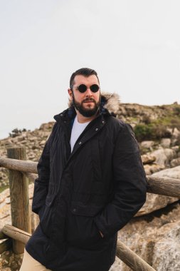 Sakallı ve bıyıklı genç adam gün batımında poz veriyor..