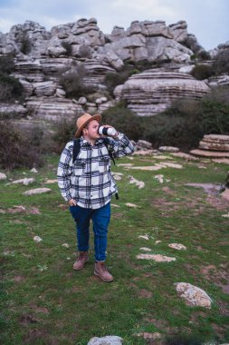Sırt çantalı ve şapkalı genç turist dağlarda.