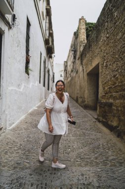 Genç ve güzel bir kadın eski bir kasabada sokakta yürüyor.