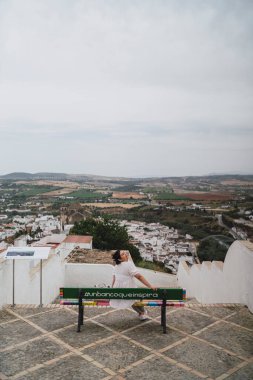 Genç bayan dağın tepesinde bankta oturuyor..