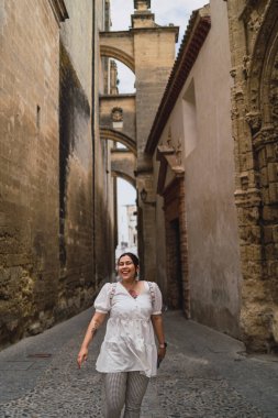 Genç ve mutlu bir kadın yaşlı kasabada yürüyor.