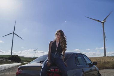 Yel değirmeni tarlasında arabasıyla poz veren çekici bir kız.