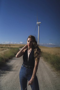 Kırsalda bir yel değirmeninin yanında poz veren genç bir kadın..