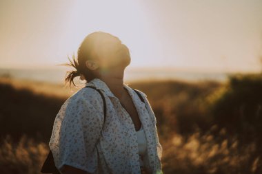 Tarlada duran uzun saçlı genç bir kadın.