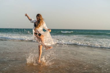 Genç kız kumsalda koşuyor..