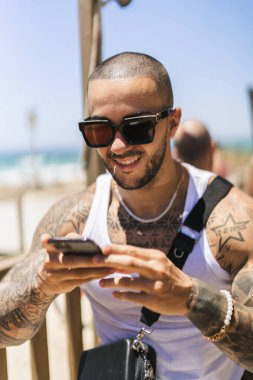 Genç adam cep telefonunun güvertesinde oturuyor.