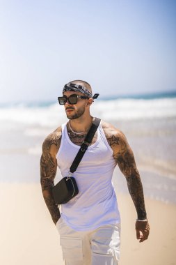 Dövmeli yakışıklı adam güneş gözlüğü takıyor.