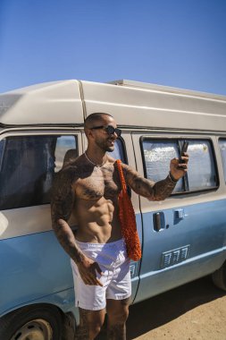 Çölde cep telefonu olan antika bir arabada bir adam.