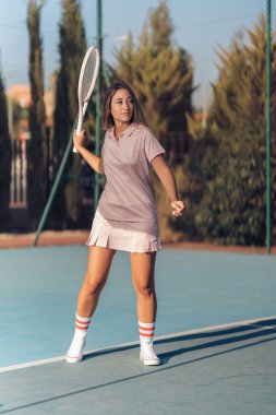 Beyaz tenis kortunda elinde raketle güzel bir kadının portresi.