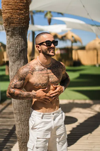 Genç adam güneşli bir günde plaj parkında duruyor..