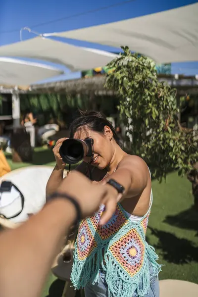 Genç bir kadın kucağında kamerayla akıllı bir telefonun fotoğrafını çekiyor..