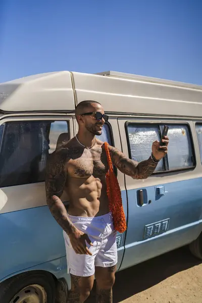 Çölde cep telefonu olan antika bir arabada bir adam.