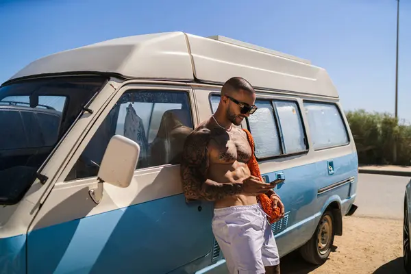 Arabada cep telefonu olan, güneş gözlüklü sakallı bir adam.