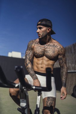 Spor salonunda bisiklet süren kaslı bir adam.