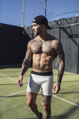 Beyzbol şapkası tutan kaslı bir adam.