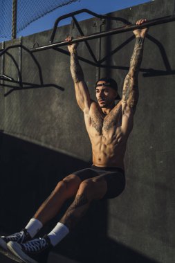 Spor salonunda halterle şınav çeken kaslı bir adam.