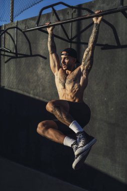 Genç kaslı adam sokakta egzersiz yapıyor.