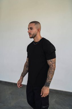 Siyah spor kıyafetli genç adam kameraya poz veriyor.