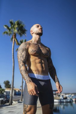 Sahilde poz veren kaslı vücutlu kaslı bir erkek.